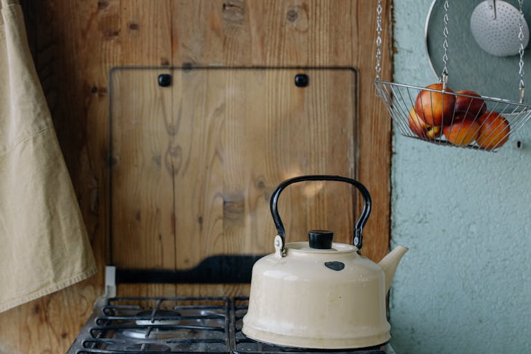 Cream kettle on a rustic stove, evoking nostalgia in a quaint kitchen setting.